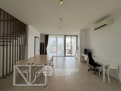 Spacious modern living room with large windows and city view, featuring minimalist furniture and sleek design.