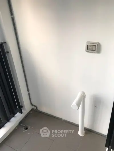 Compact balcony area with railing and utility pipe, ideal for small outdoor setups.