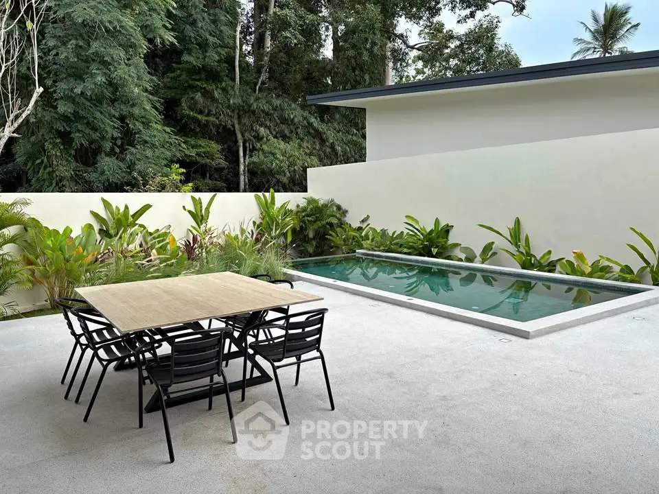Modern outdoor patio with sleek pool and lush greenery, perfect for relaxation and entertaining.