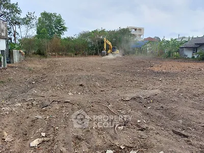 Spacious cleared land ready for development with excavator in action, ideal for new construction projects.
