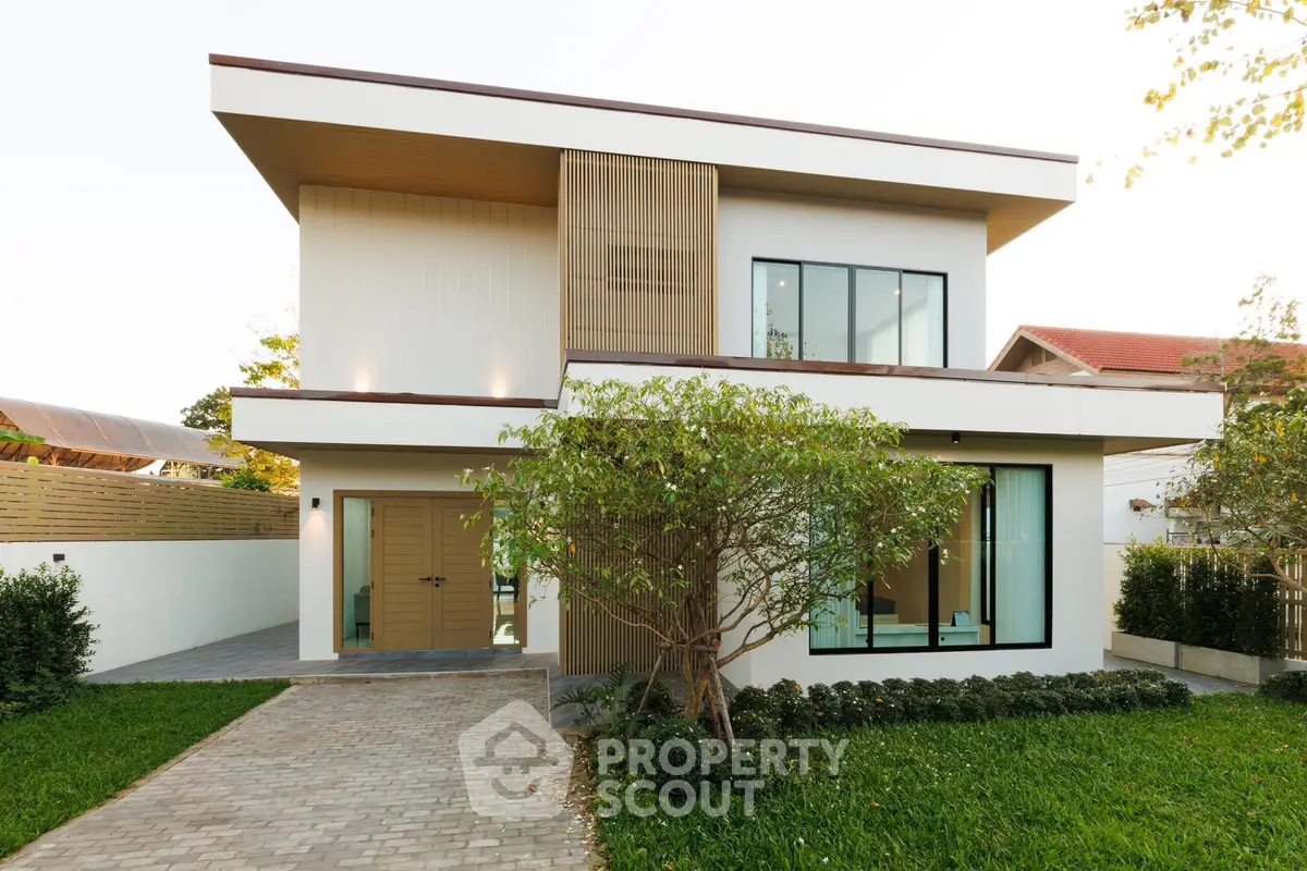 Modern two-story house with large windows and lush green garden