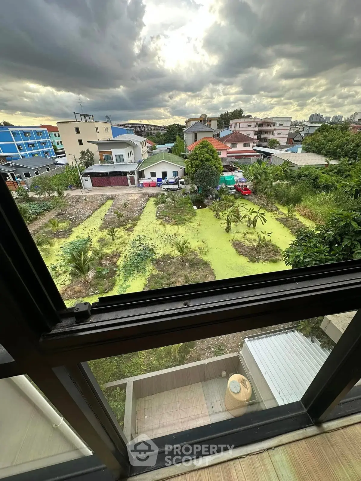 Stunning view from a high-rise window overlooking lush gardens and residential area.