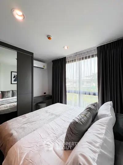 Modern bedroom with large window and stylish decor in a cozy apartment.