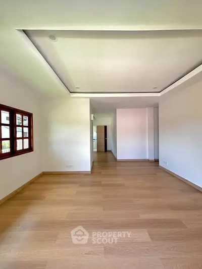 Spacious open-plan living area with wooden flooring and natural light.