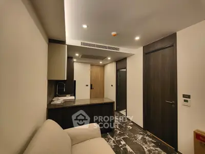 Modern interior with sleek kitchen and cozy living area, featuring dark wood accents and contemporary lighting.