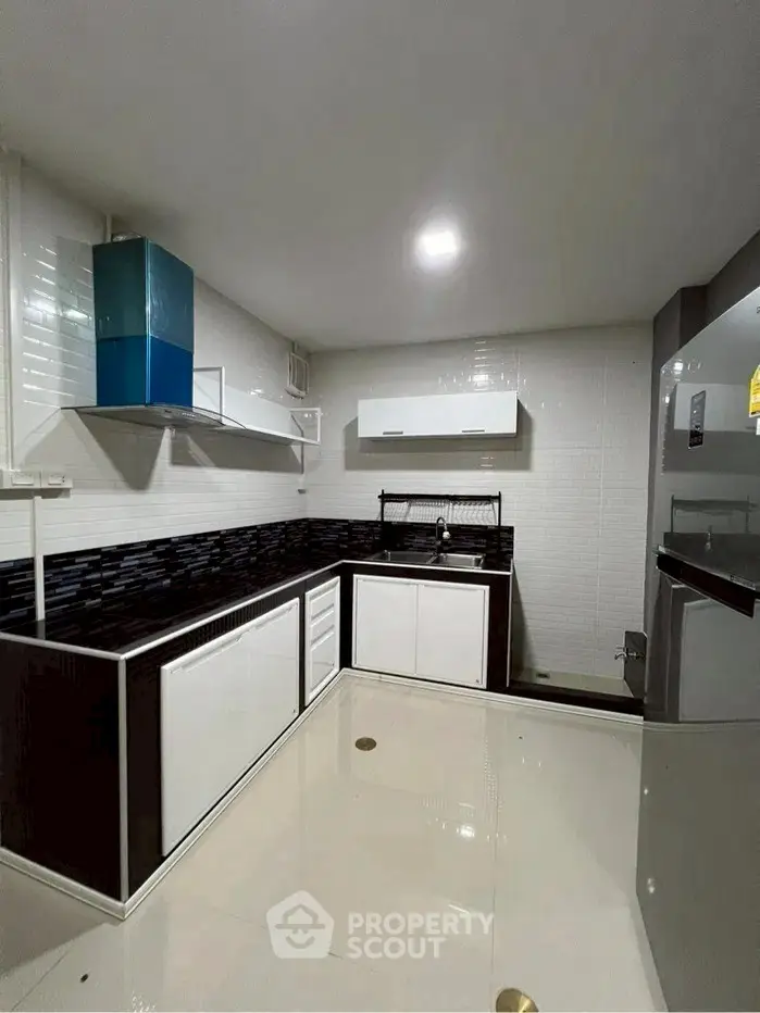 Modern kitchen with sleek black and white design, featuring a gas stove and ample storage space.