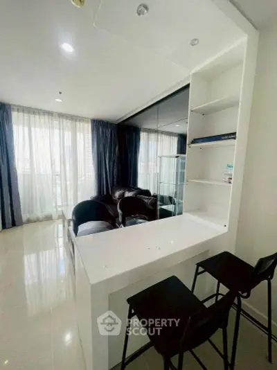 Modern living room with sleek white bar counter and large windows for natural light.