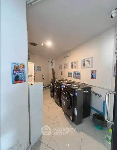 Modern laundry room with sleek washing machines and tiled flooring, ideal for convenient living.