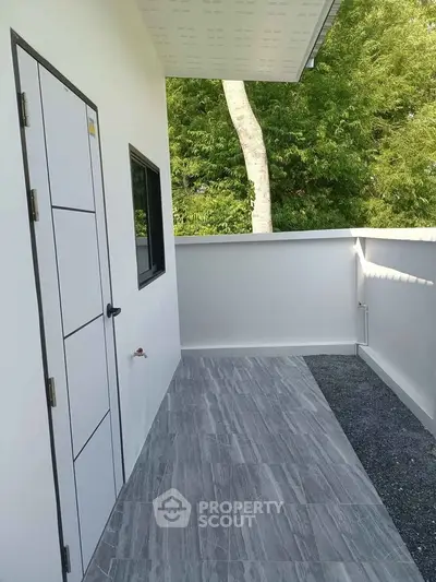 Modern balcony with sleek tiled flooring and lush green view, perfect for relaxation.