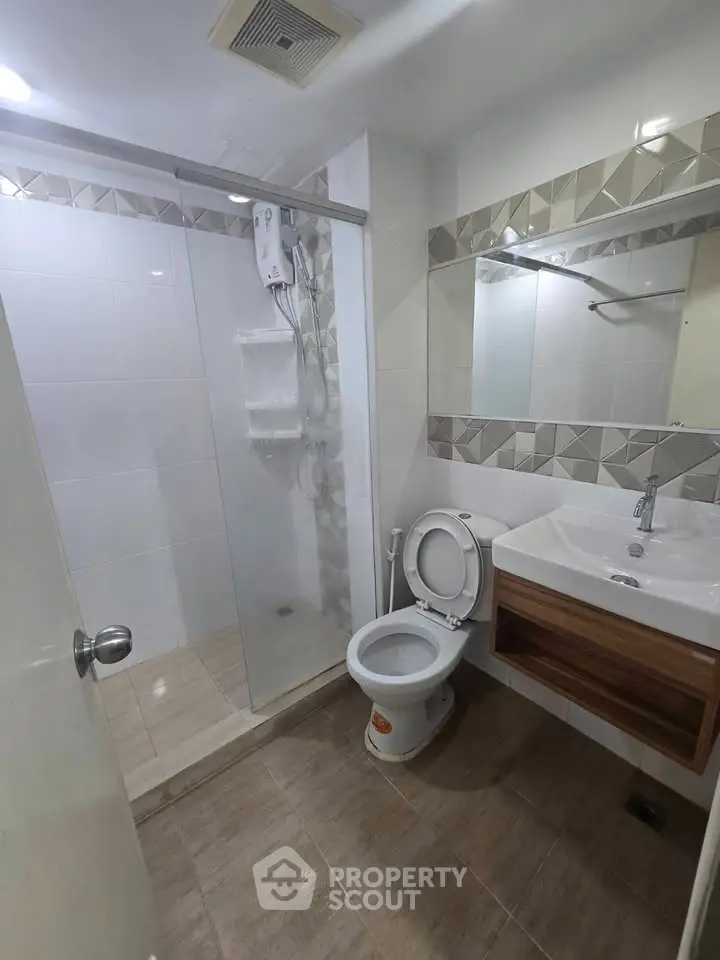 Modern bathroom with glass shower and stylish vanity in contemporary apartment.