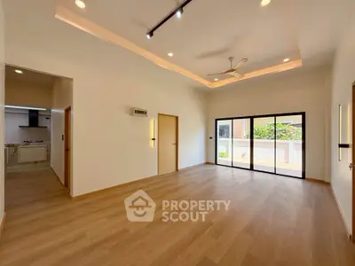 Spacious modern living room with wooden flooring and large windows offering natural light.