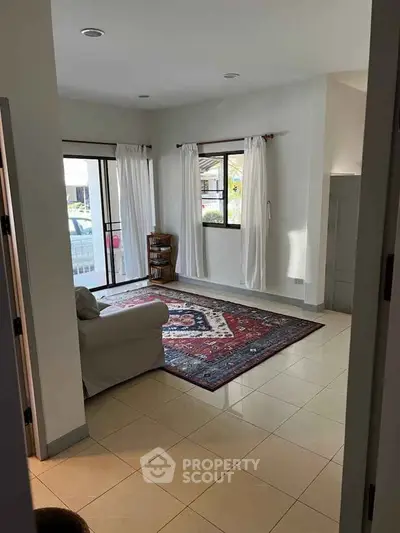 Spacious living room with large windows and elegant rug, perfect for relaxation.