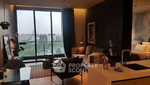 Modern open-plan living room with large windows and city view, featuring stylish furniture and cozy ambiance.