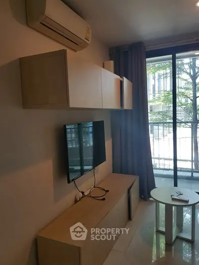 Modern living room with wall-mounted TV and air conditioning, featuring sleek furniture and large window.