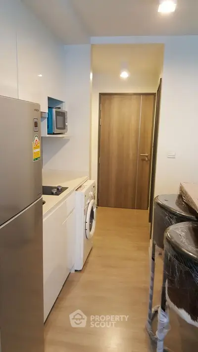 Modern kitchen with sleek appliances and washing machine in compact layout