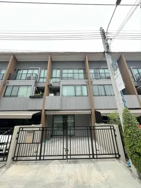 Modern townhouse exterior with gated entrance and multiple balconies.