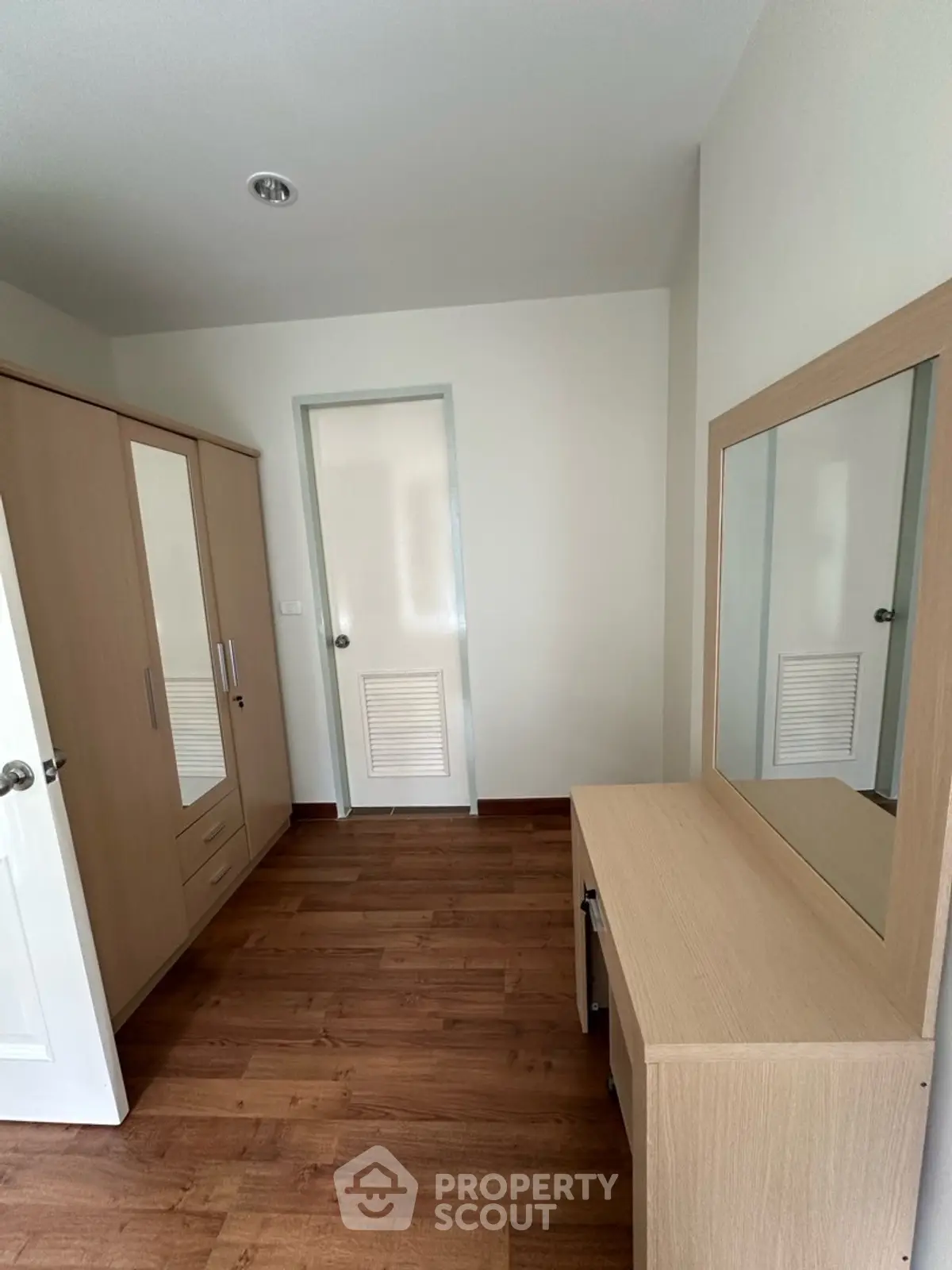 Spacious bedroom with wooden flooring and modern wardrobe