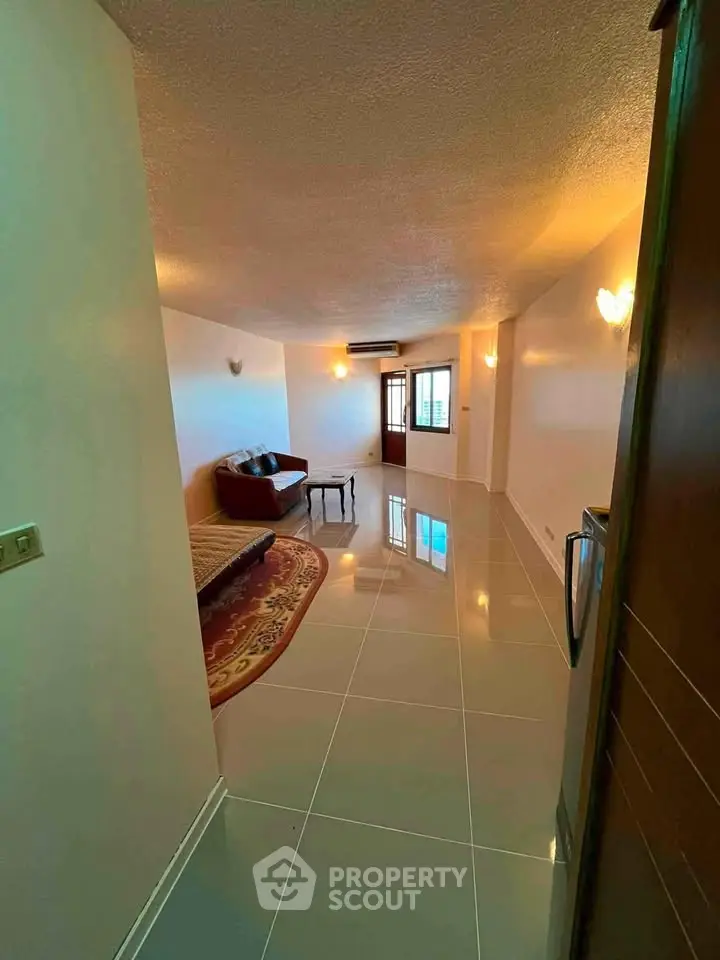 Spacious living room with modern tile flooring and cozy seating area, perfect for relaxation.