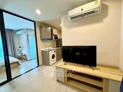 Modern apartment interior with open living room and kitchen, featuring air conditioning and washing machine.