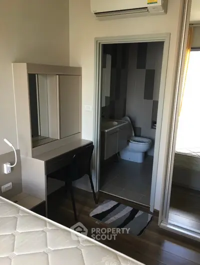 Modern bedroom with ensuite bathroom and study area, featuring sleek furniture and air conditioning.