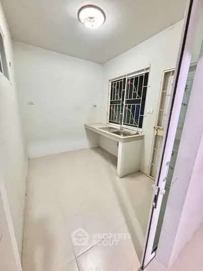 Minimalist kitchen with white tiles and metal sink, perfect for compact living spaces.