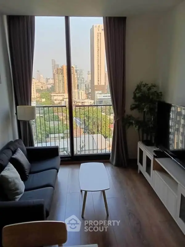 Modern living room with large window offering stunning city view, cozy seating, and sleek decor.