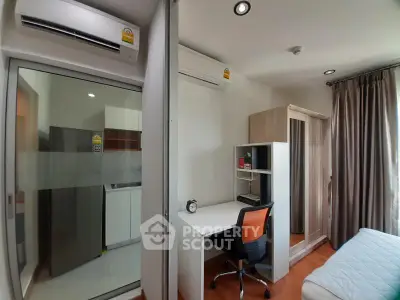 Modern bedroom with study area and kitchen view, featuring air conditioning and sleek furniture.