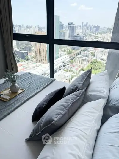 Luxurious bedroom with stunning city view from high-rise window, featuring elegant decor and plush bedding.