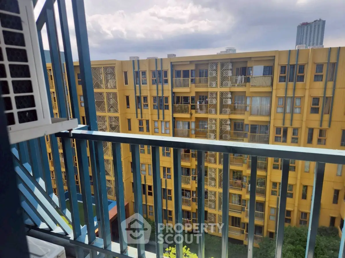 Modern urban apartment building with vibrant yellow facade and balcony view.