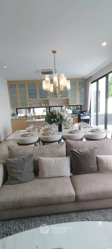 Luxurious open-plan living room with elegant dining area and modern kitchen, featuring chic decor and ample natural light.