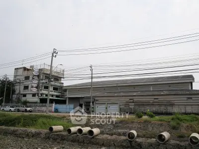 Industrial warehouse exterior with adjacent building and open land