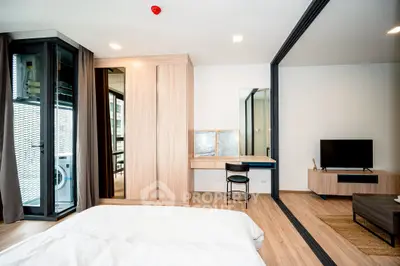 Modern bedroom with sliding glass doors, wooden flooring, and a compact laundry area.