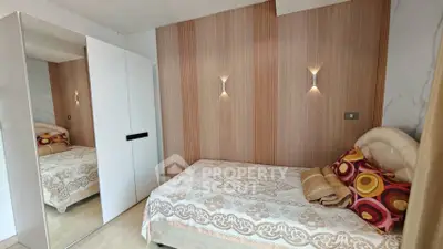 Cozy bedroom with modern design, featuring a stylish bed and mirrored wardrobe, perfect for urban living.
