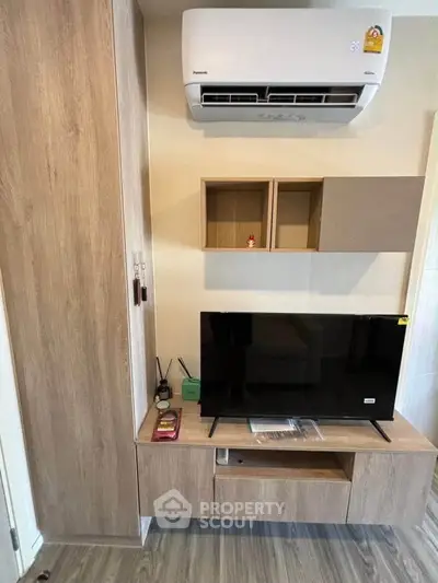 Modern living room with sleek wooden furniture and mounted air conditioner, perfect for cozy urban living.