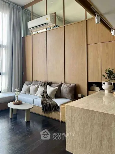 Modern living room with sleek design and neutral tones, featuring a cozy seating area and stylish decor.