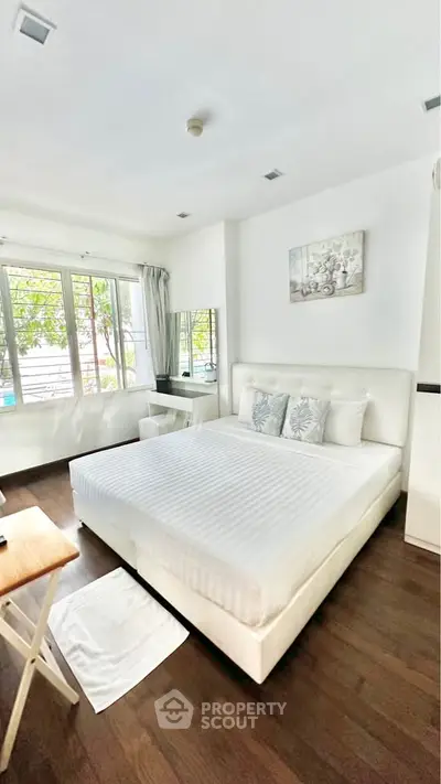Spacious bedroom with elegant decor and large windows offering natural light.