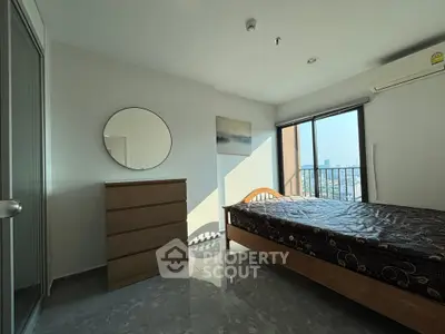 Bright bedroom with city view, featuring a wooden bed and dresser, ideal for urban living.