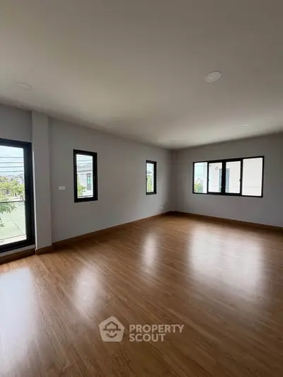 Spacious empty room with large windows and wooden flooring, perfect for customization.