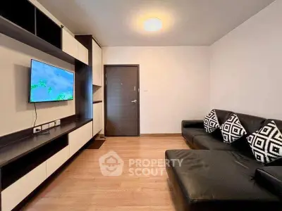 Modern living room with sleek black sofa and wall-mounted TV in stylish apartment.