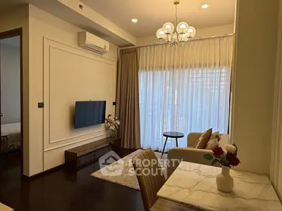 Elegant living room with modern decor, featuring a wall-mounted TV, chic chandelier, and cozy seating area.