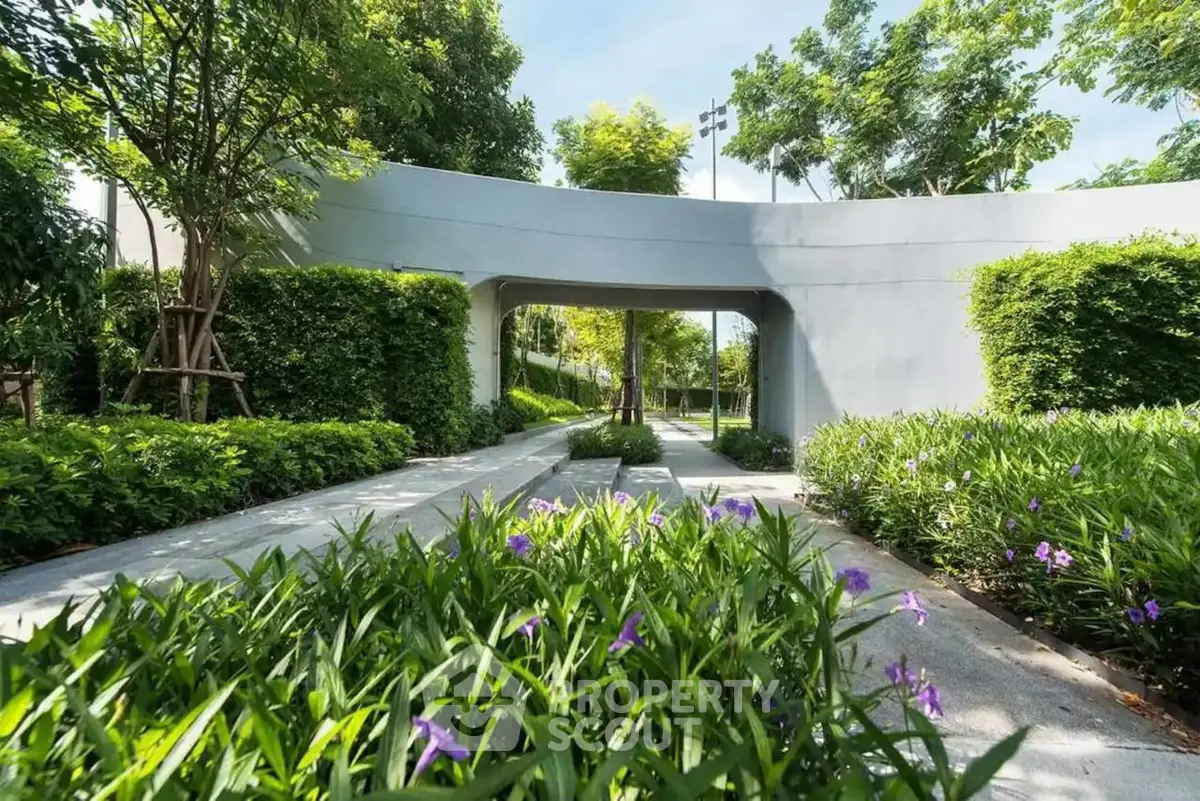 Lush garden pathway with modern architectural archway and vibrant greenery.