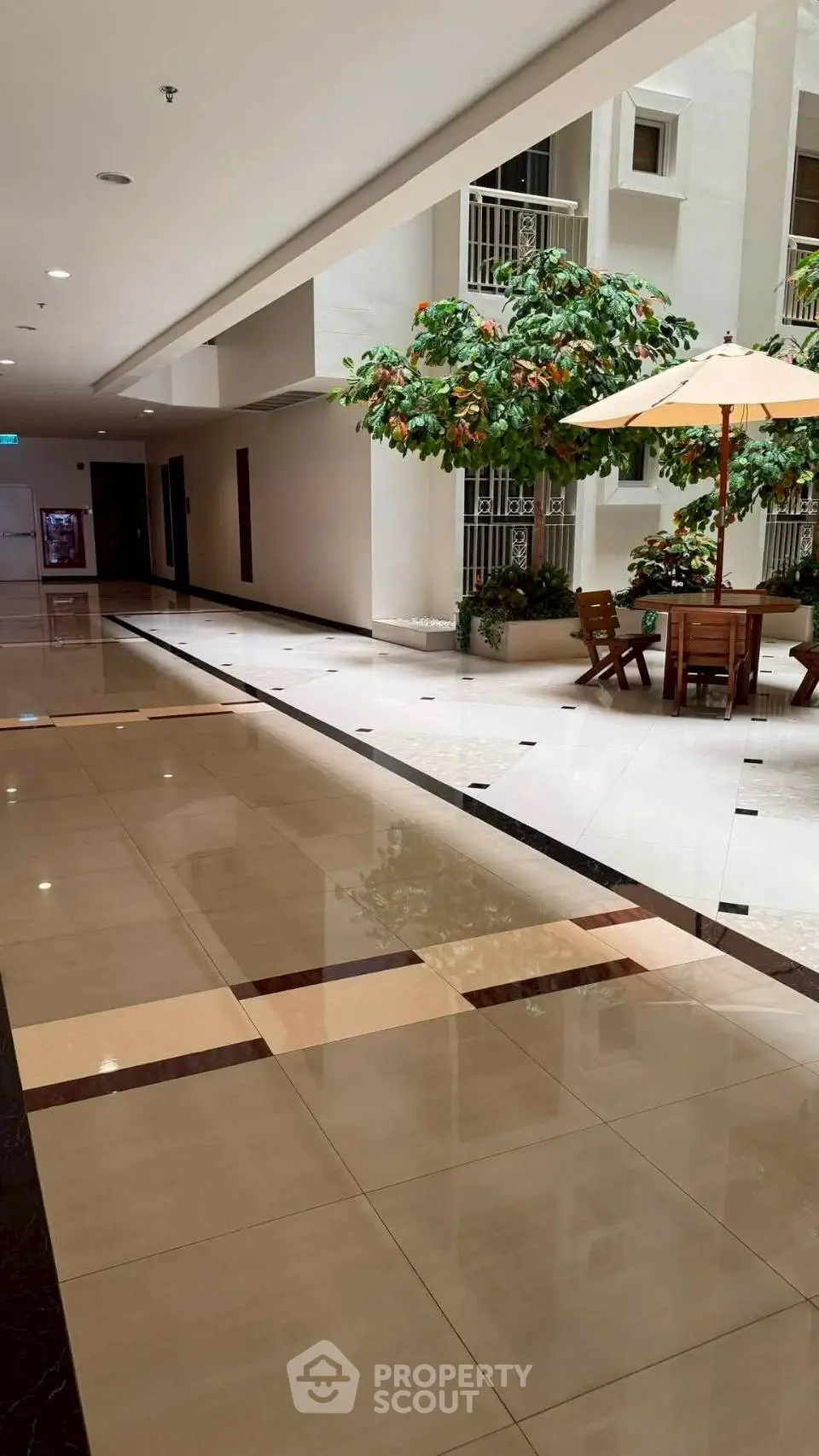 Elegant indoor atrium with seating area and lush greenery in modern building.