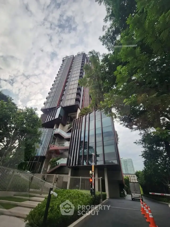 Modern high-rise building with lush greenery and sleek architectural design.