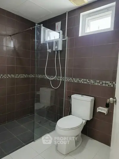 Modern bathroom with glass shower and tiled walls in real estate property.