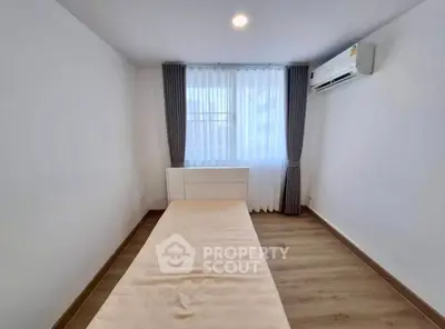 Minimalist bedroom with single bed and air conditioning in modern apartment.