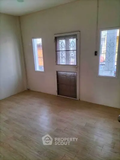 Spacious empty room with wooden flooring and secure windows, ideal for customization.