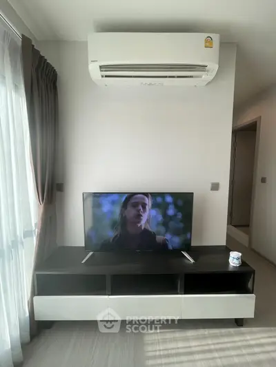 Modern living room with air conditioning and TV unit, featuring sleek furniture and natural light.