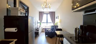 Modern apartment interior with open kitchen and cozy living area, featuring stylish lighting and large window.