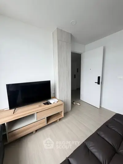 Modern living room with sleek TV stand and open door, showcasing minimalist design and bright ambiance.