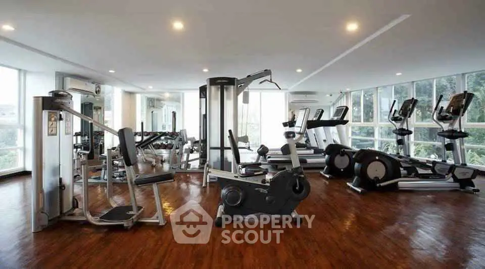 Spacious modern gym with state-of-the-art equipment and large windows offering natural light.